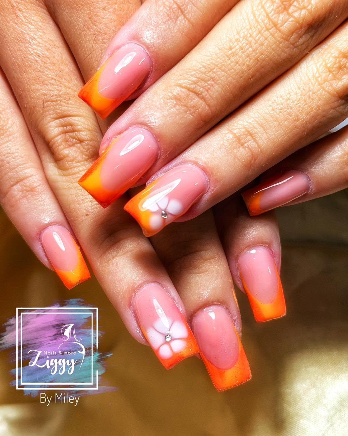 Bright orange French tip nails with white flower nail art